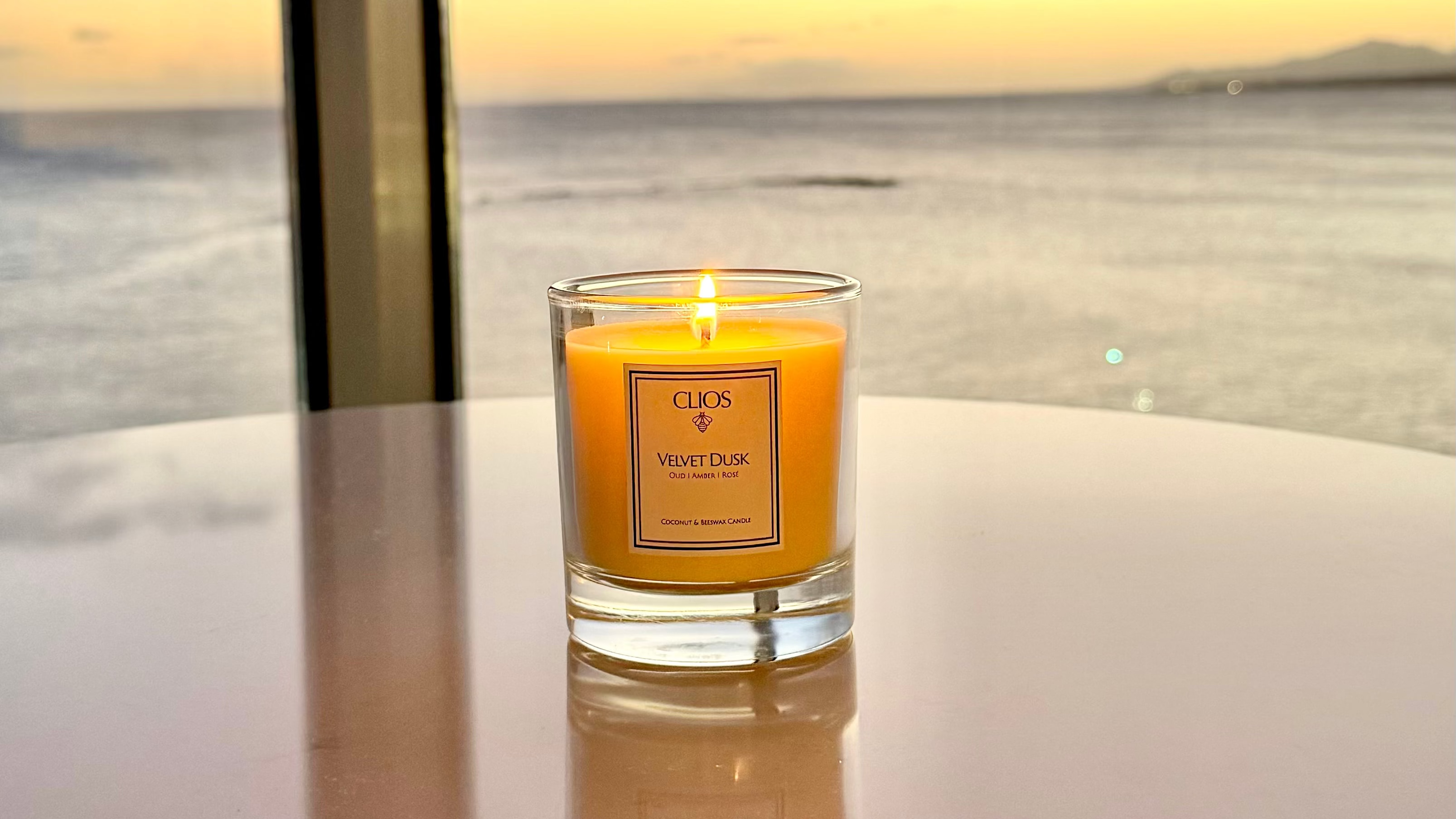 Candle on a table with a scenic view of water and sky in the background